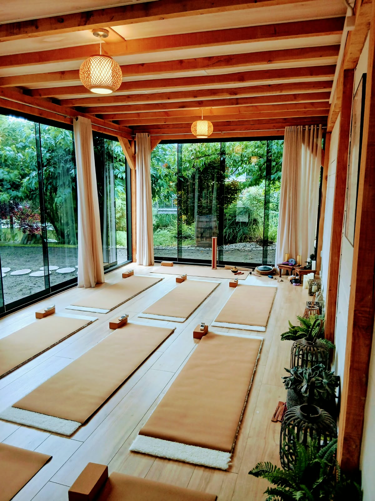 Yoga in Capelle aan den IJssel: de studio van SensZenjoy met yogamatten onder houten balken en uitzicht op de tuin